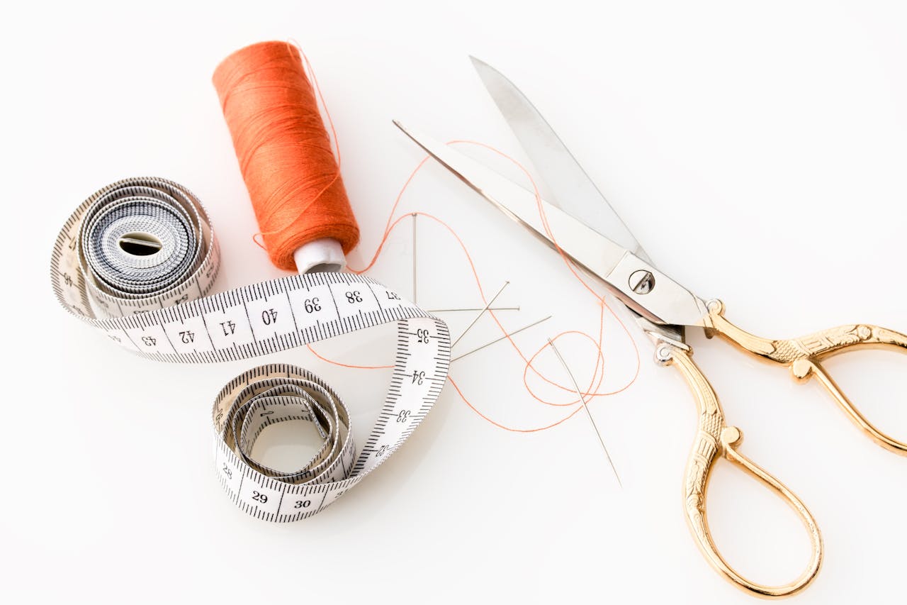 About Photo of sewing essentials: scissors, thread, needles, and tape measure on a white background.