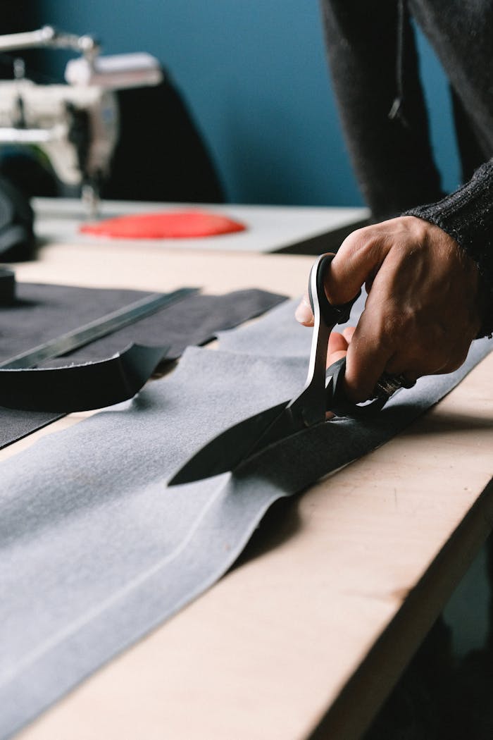 Services A tailor precisely cuts fabric on a workbench with professional scissors.