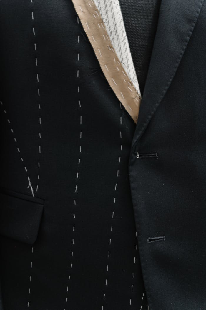 A detailed view of an unfinished tailored suit jacket with visible stitching lines.